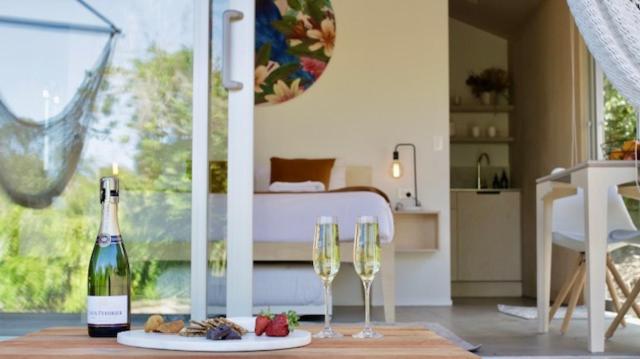 a room with two glasses of wine and a bed at One O One Cabins, Waiheke Island in Oneroa