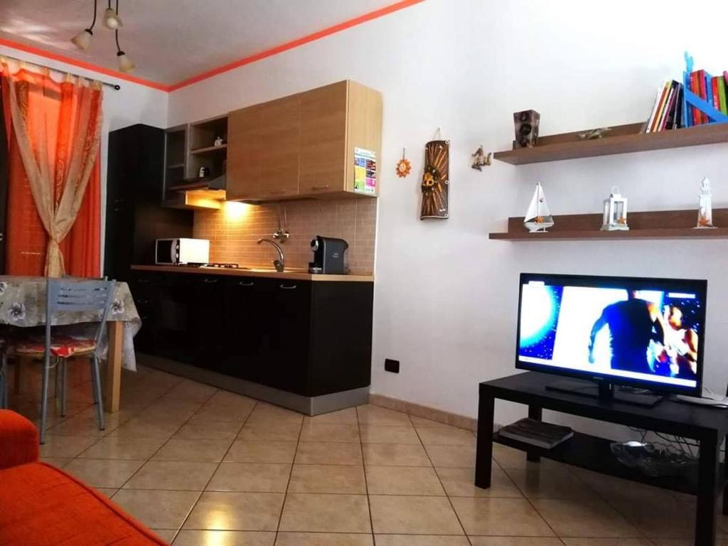 a living room with a television and a kitchen at Casa Isulidda in San Vito lo Capo