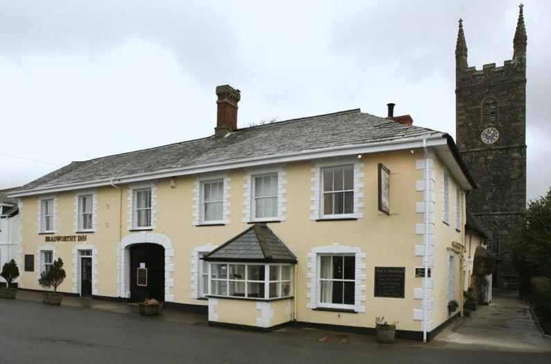 un edificio blanco con un reloj a un lado en The Bradworthy Inn, en Holsworthy