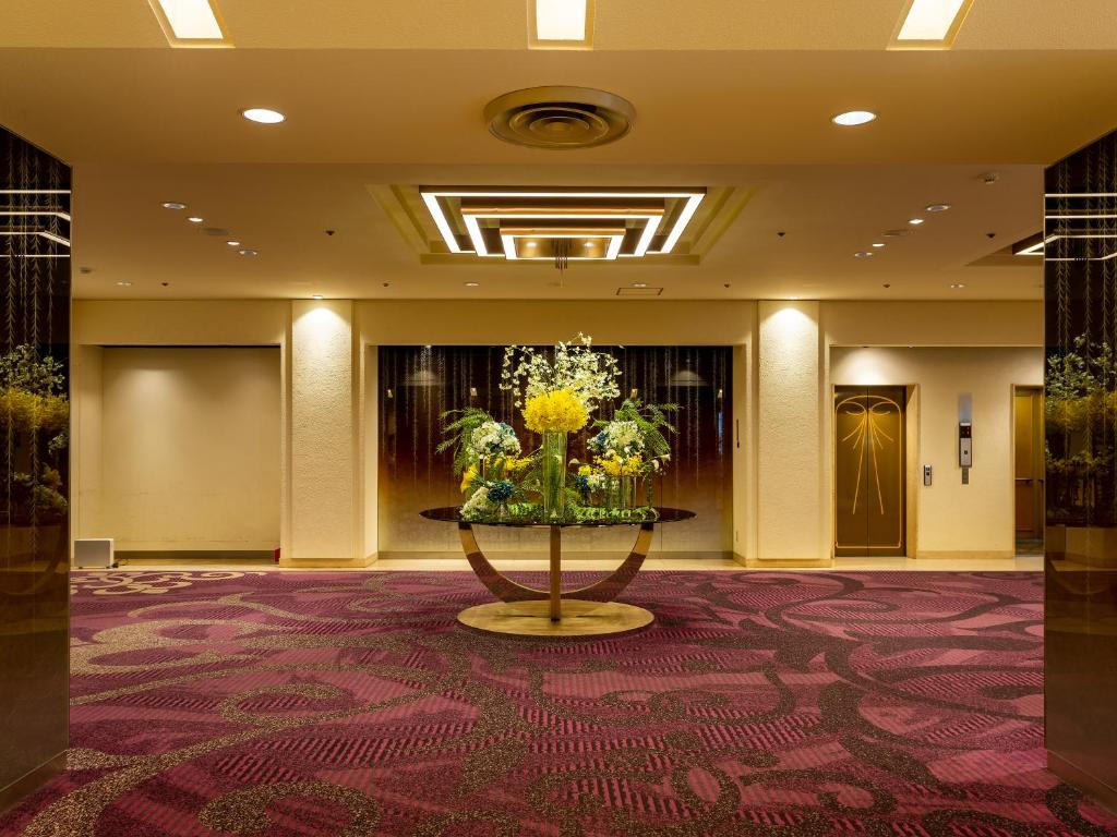 a lobby with a vase of flowers on a table at Rihga Hotel Zest Takamatsu in Takamatsu