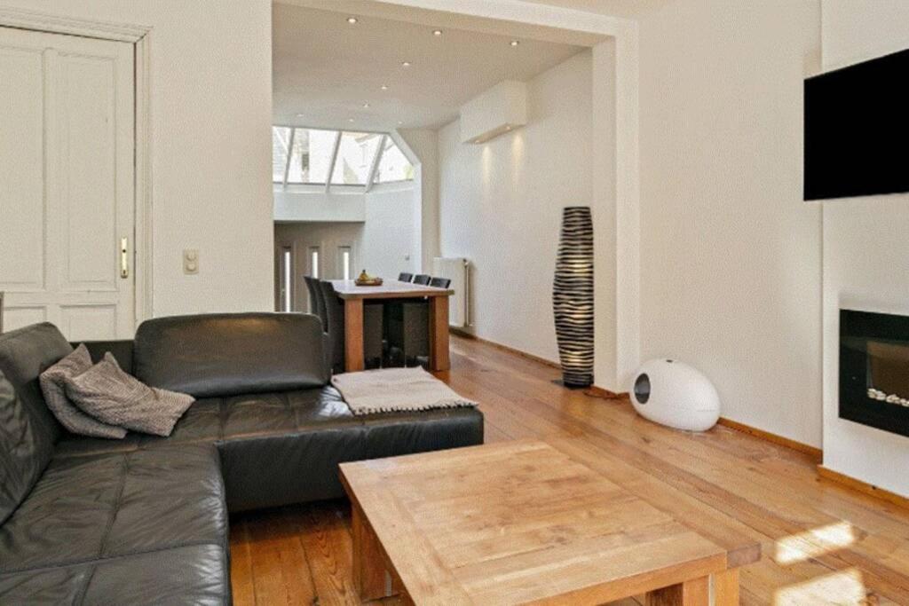 een woonkamer met een zwarte leren bank en een tafel bij Villa Victorina in Oostende