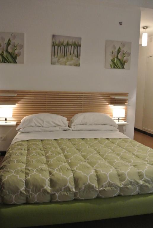 a large bed in a bedroom with two paintings on the wall at B&B Via Dei Templi in Agrigento