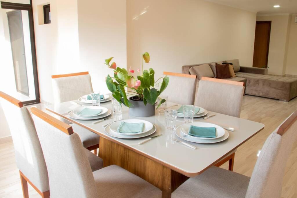 mesa de comedor con platos y sillas y sofá en Apartamento amplio y acogedor en Ciudad del Este, en Ciudad del Este