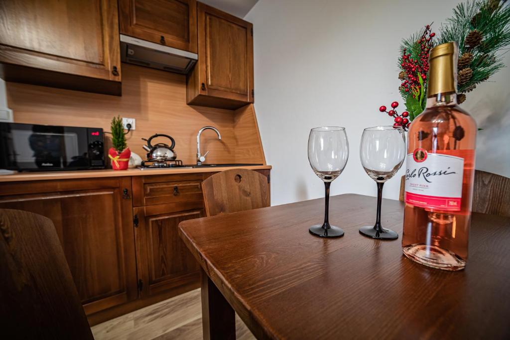 a bottle of wine sitting on a table with two wine glasses at Chatki Nad Potokiem Gronków in Gronków