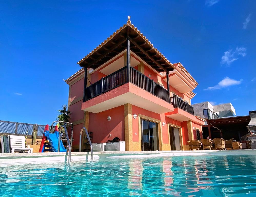 a building with a swimming pool in front of a house at Luxury 5 star Villa Violetta with amazing sea view, jacuzzi and heated pool in San Agustin