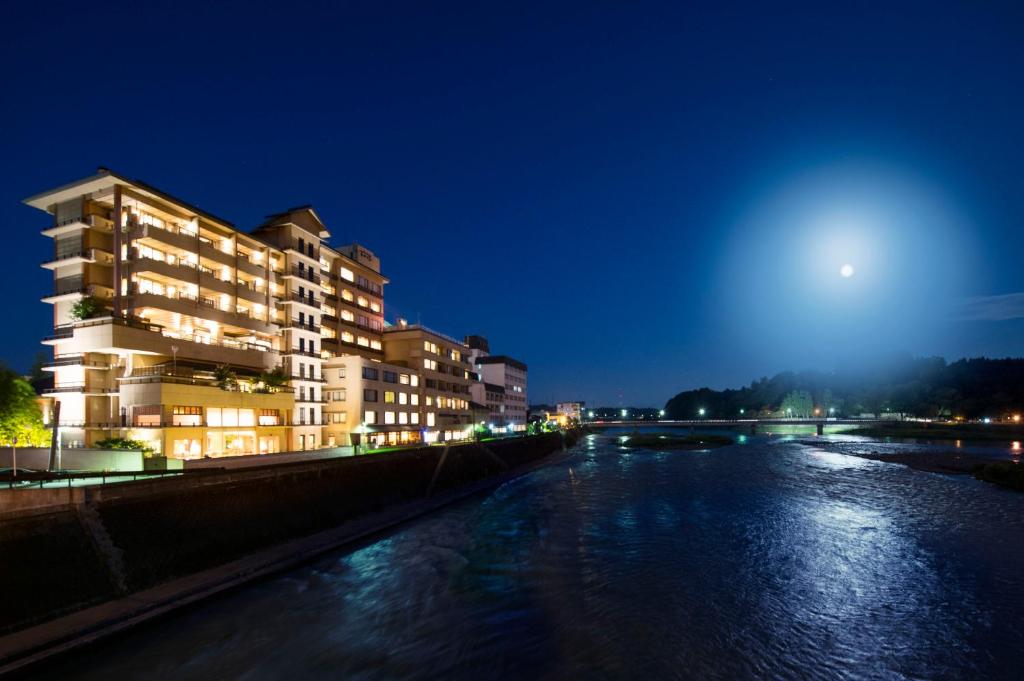 un edificio vicino a un fiume di notte di Ryokan Ayu no Sato a Hitoyoshi