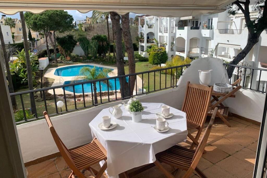 a white table and chairs on a balcony with a pool at COSTA DEL SOL SUN BEACH AMAZING APARTMENT,300 MTS BEACH.3BED. in Estepona