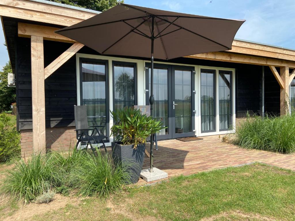 une maison avec un parasol sur une terrasse dans l'établissement Hof van Lenthe appartement De Bosrand, à Dalfsen