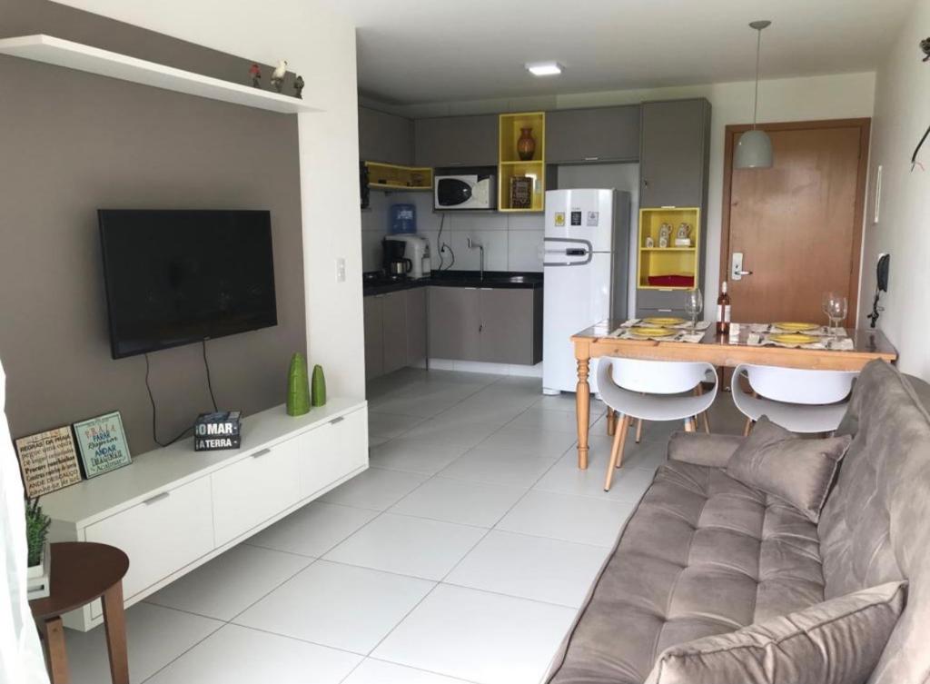a living room with a couch and a table and a kitchen at Iloa Apartamento Lindo in Barra de São Miguel