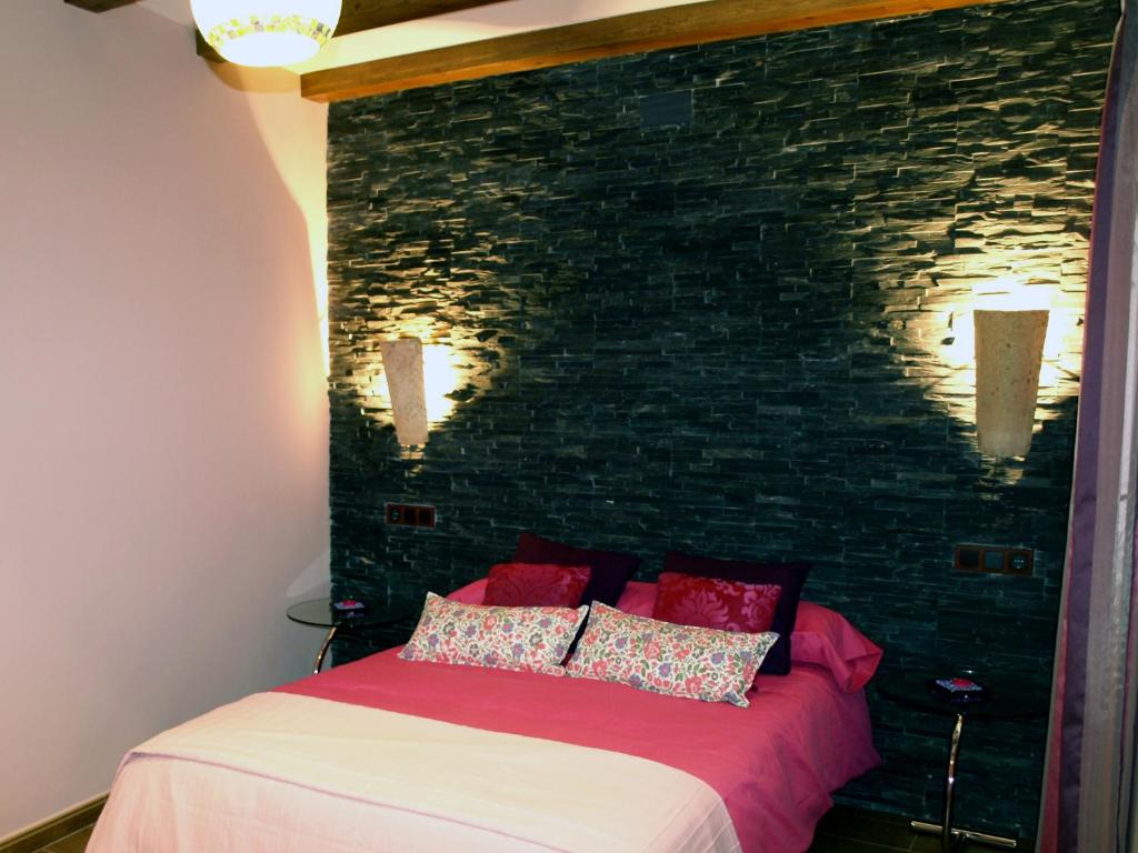 a bedroom with a bed with a brick wall at Apartamentos Rurales El Palomar in Villar del Humo