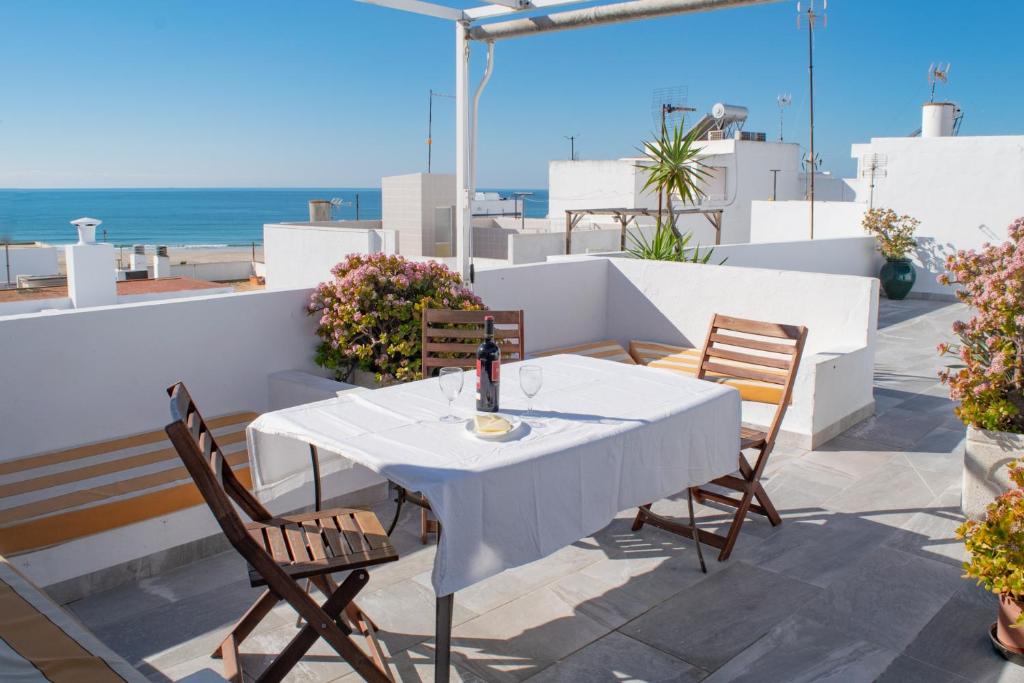 een witte tafel en stoelen op een balkon met uitzicht op de oceaan bij Conil town house with roof terrace and great views, Baluarte in Conil de la Frontera