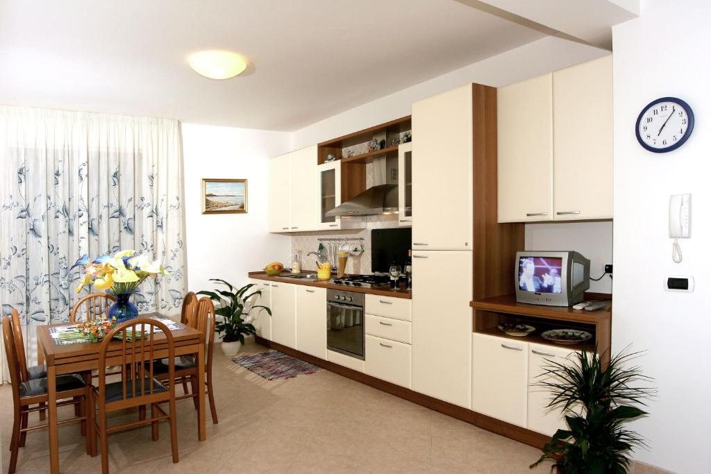 a kitchen and dining room with a table and a clock at Verde Mare "Appartamenti per Vacanze" in Tortoreto Lido