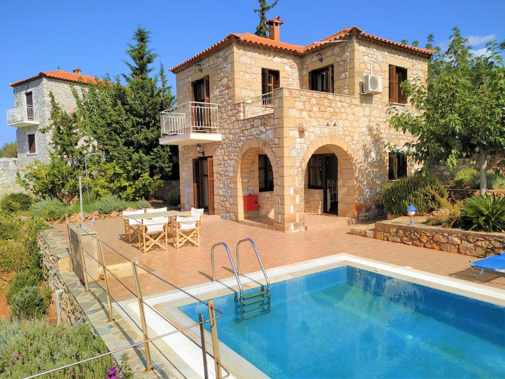 a villa with a swimming pool in front of a house at ORATO VILLAGE in Pirgos