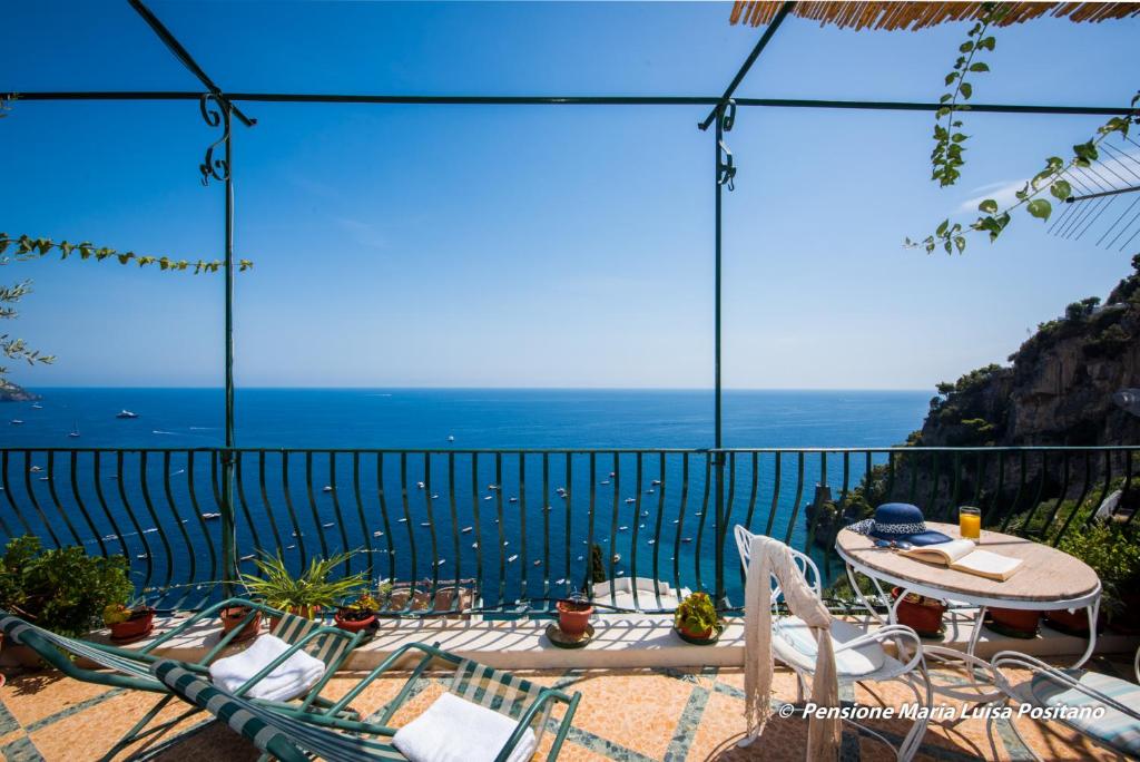 un patio con tavolo, sedie e vista sull'oceano di Pensione Maria Luisa a Positano