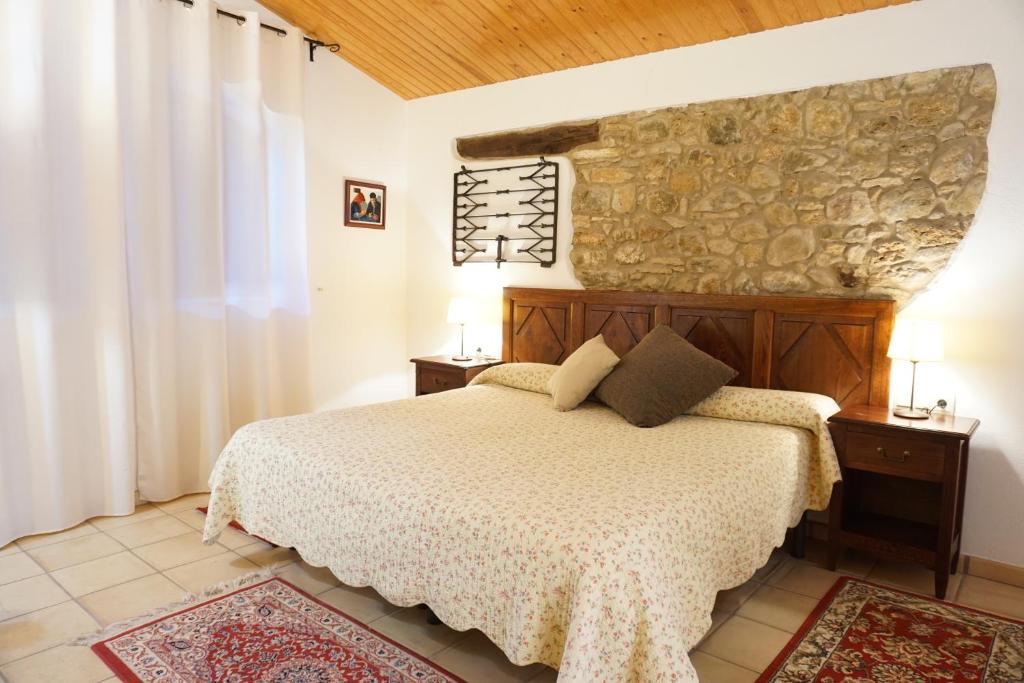 1 dormitorio con cama y pared de piedra en La Sala de Camós, en Camós