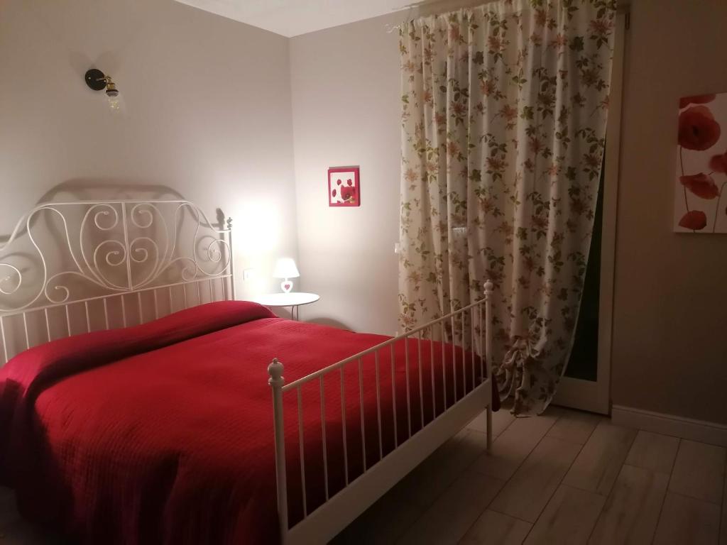 ein Schlafzimmer mit einem Bett mit einer roten Decke und einem Fenster in der Unterkunft Bilocale Papavero, Magnolia o Girasole in San Felice del Benaco