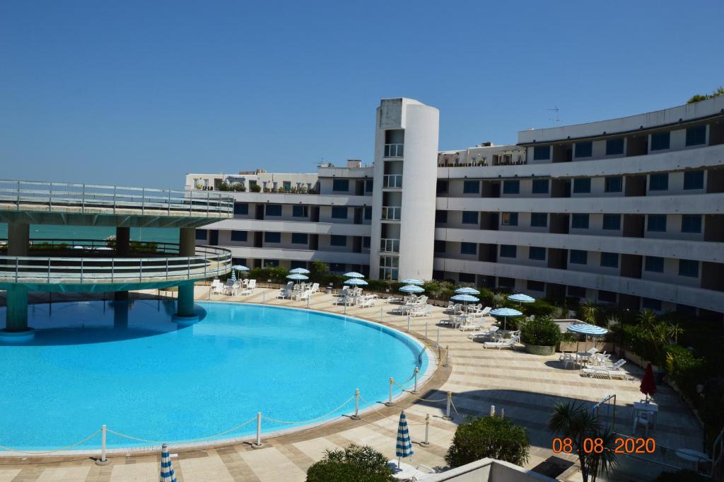 una grande piscina con sedie e ombrelloni accanto a un edificio di Appartamento Paradiso Azzurro a Porto Recanati
