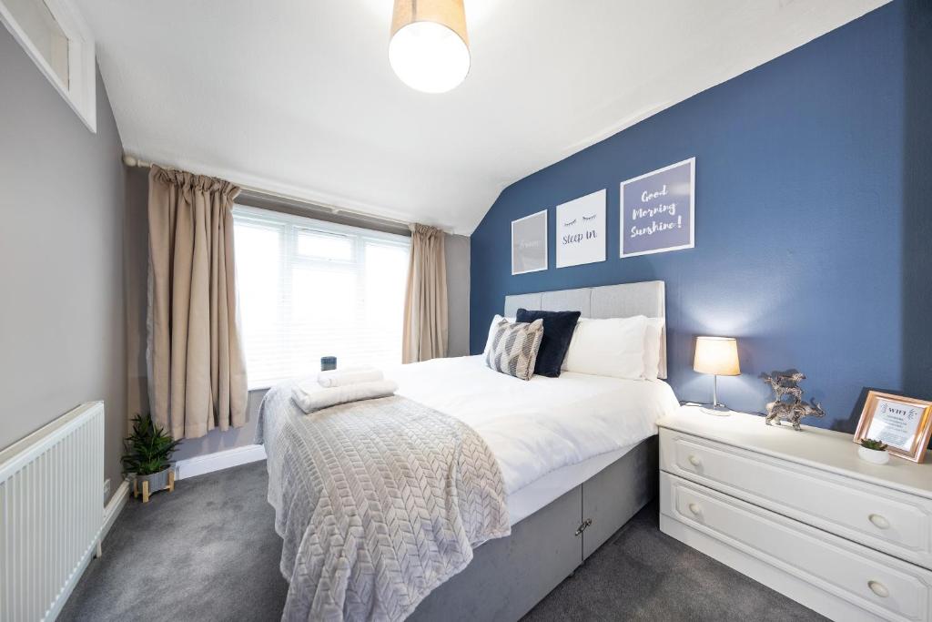 Inspire Homes - Joe's Cottage في ساوثهام: غرفة نوم بسرير كبير بجدار ازرق