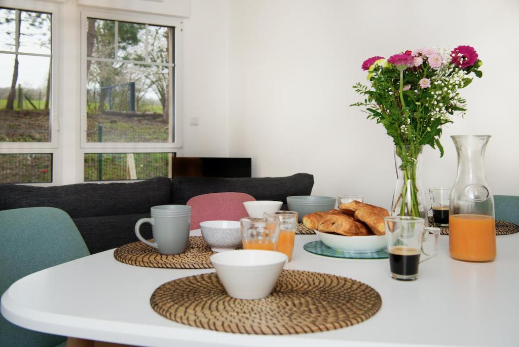 een tafel met een witte tafel met een vaas met bloemen bij Séjour chaleureux en Baie de Somme in Saint-Valery-sur-Somme