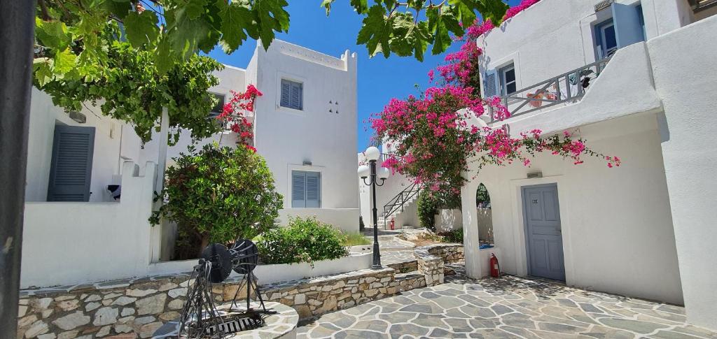 a group of white buildings with flowers in a street at Teoria Paros - Matsas Windmill in Naousa