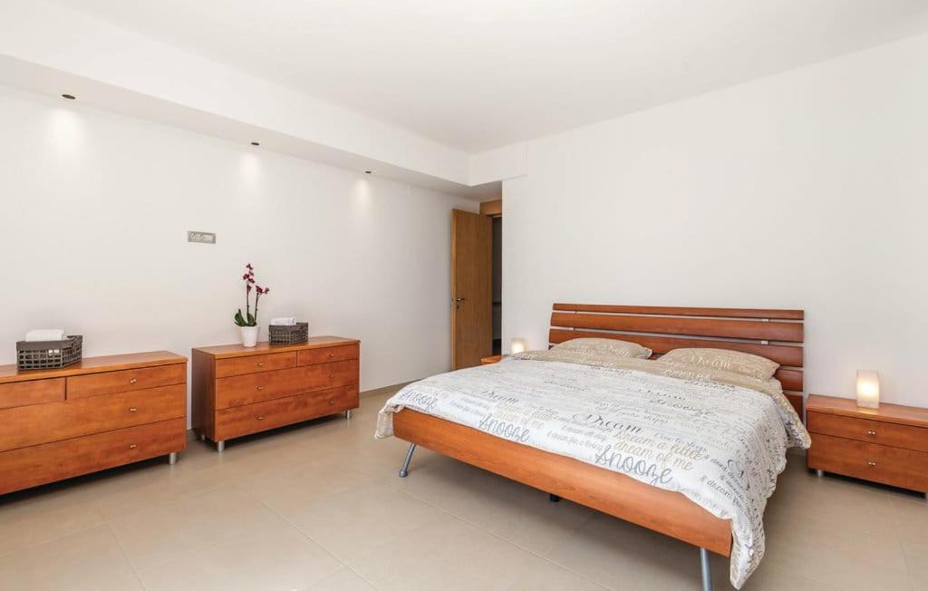 a bedroom with a large bed and two wooden dressers at Apartman Villa Pećine in Rijeka