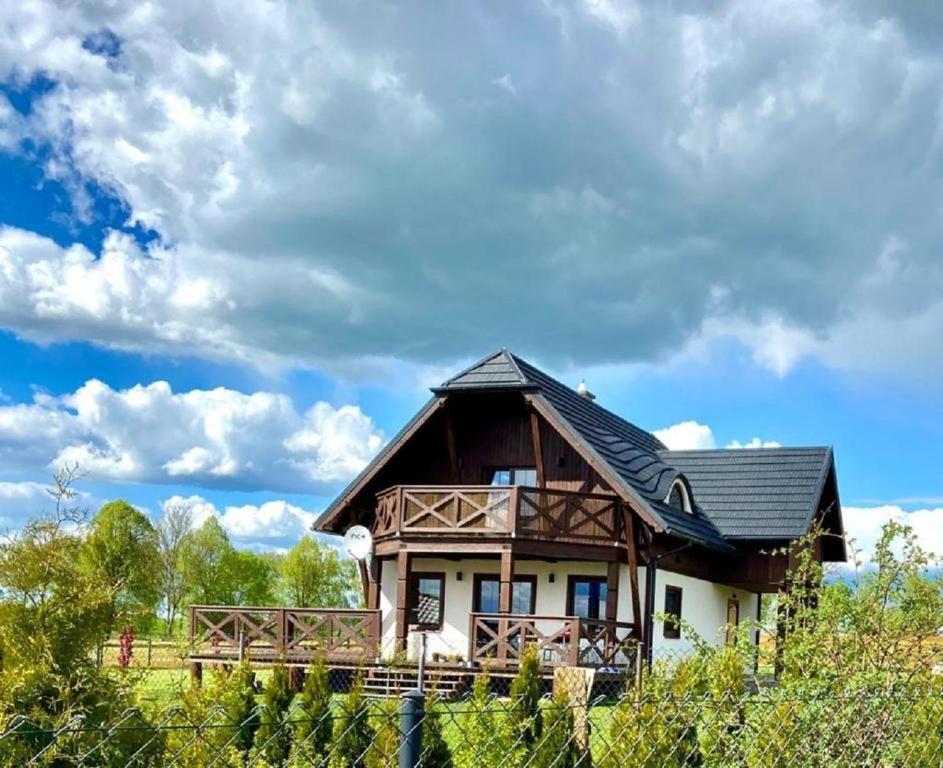 une maison avec un toit noir dans un champ dans l'établissement Mazurska Osada nad jeziorem Orzysz, à Skomack Wielki
