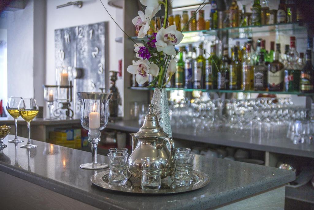 a bar with glasses and a vase of flowers on a counter at Hôtel Le Méditerranée in Hyères