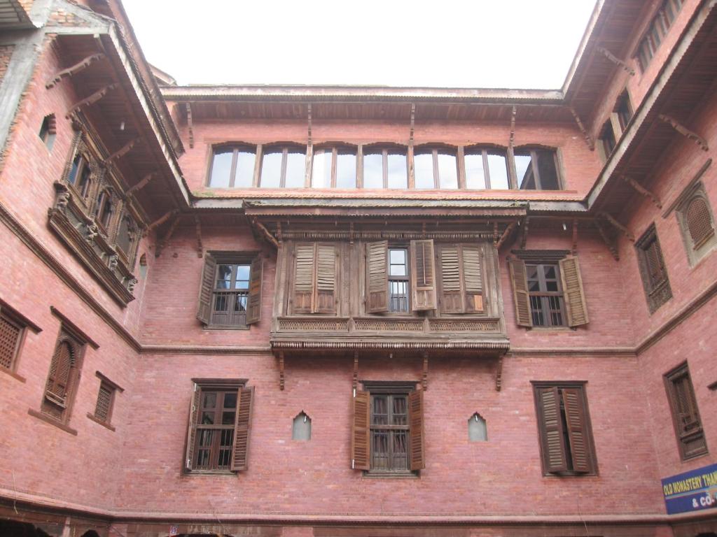 een groot gebouw van rode baksteen met ramen en houten luiken bij World Heritage Hotel and Apartments in Kathmandu