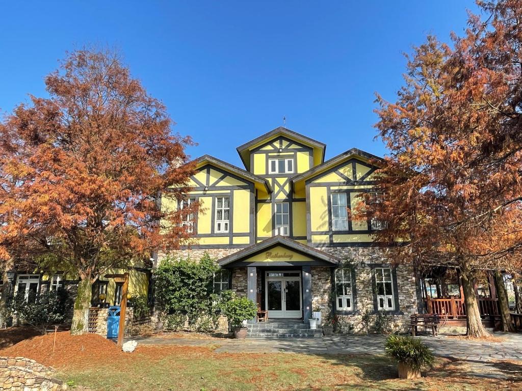 a large yellow and black house with trees at Rothenburg Lodge in Wujie