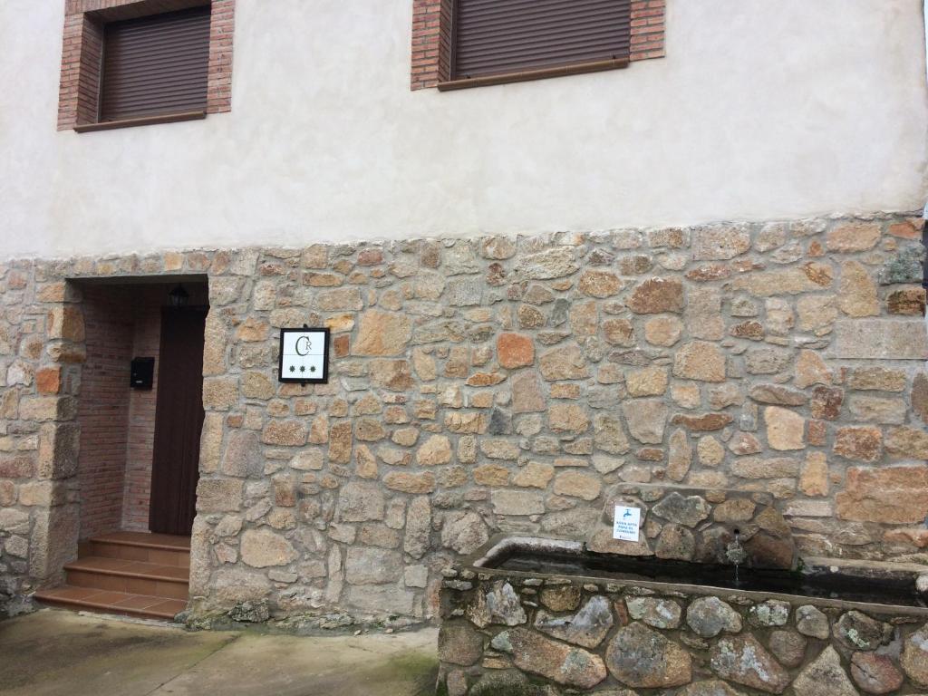un edificio con una pared de piedra con un reloj. en Casa Rural El Pilón, en Santibáñez el Alto