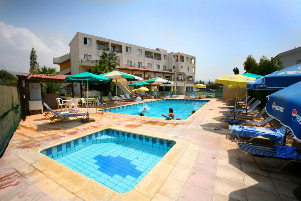 uma piscina com cadeiras e guarda-sóis e um hotel em Petsas Apartments em Coral Bay