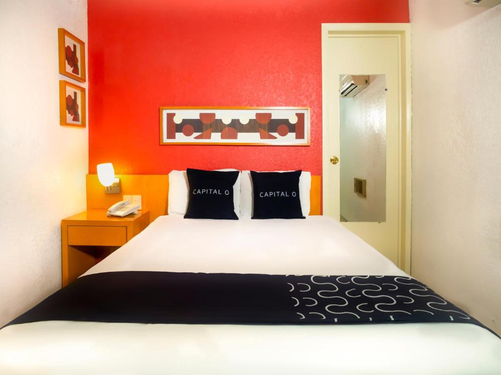 - une chambre avec un lit et un mur rouge dans l'établissement Hotel Regis, à Mexicali