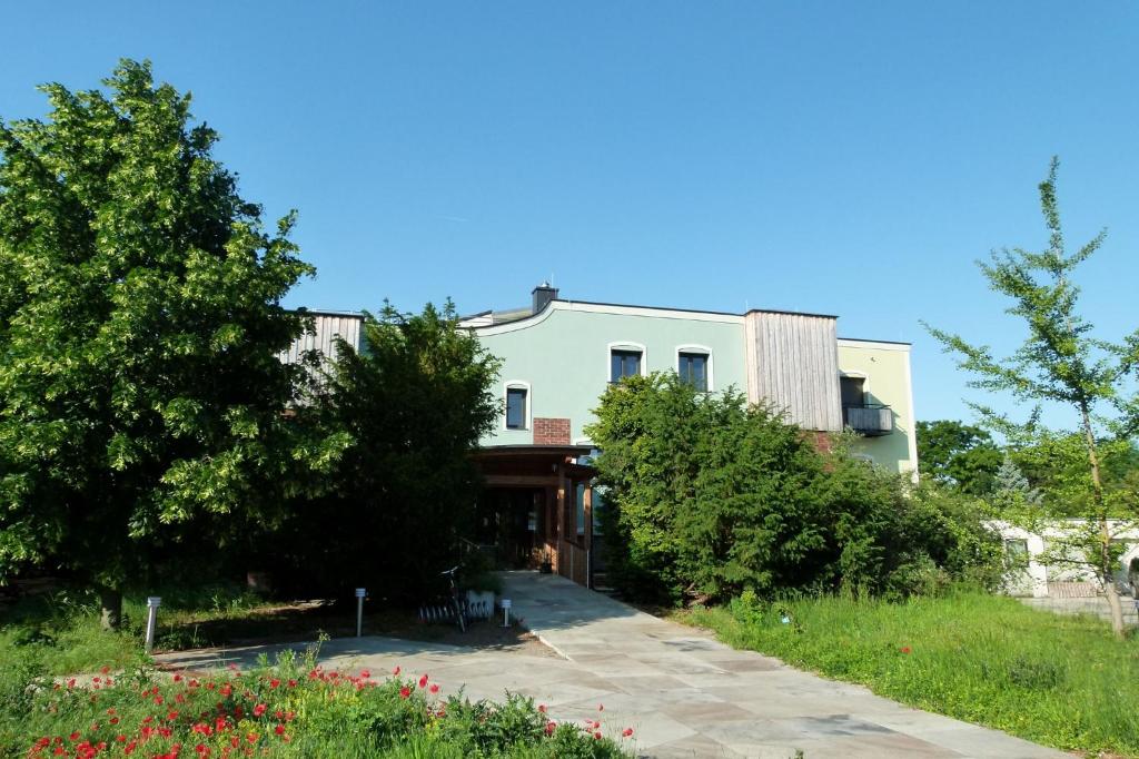 ein großes weißes Haus mit Bäumen und Blumen in der Unterkunft Haus Monti in Maria Lanzendorf