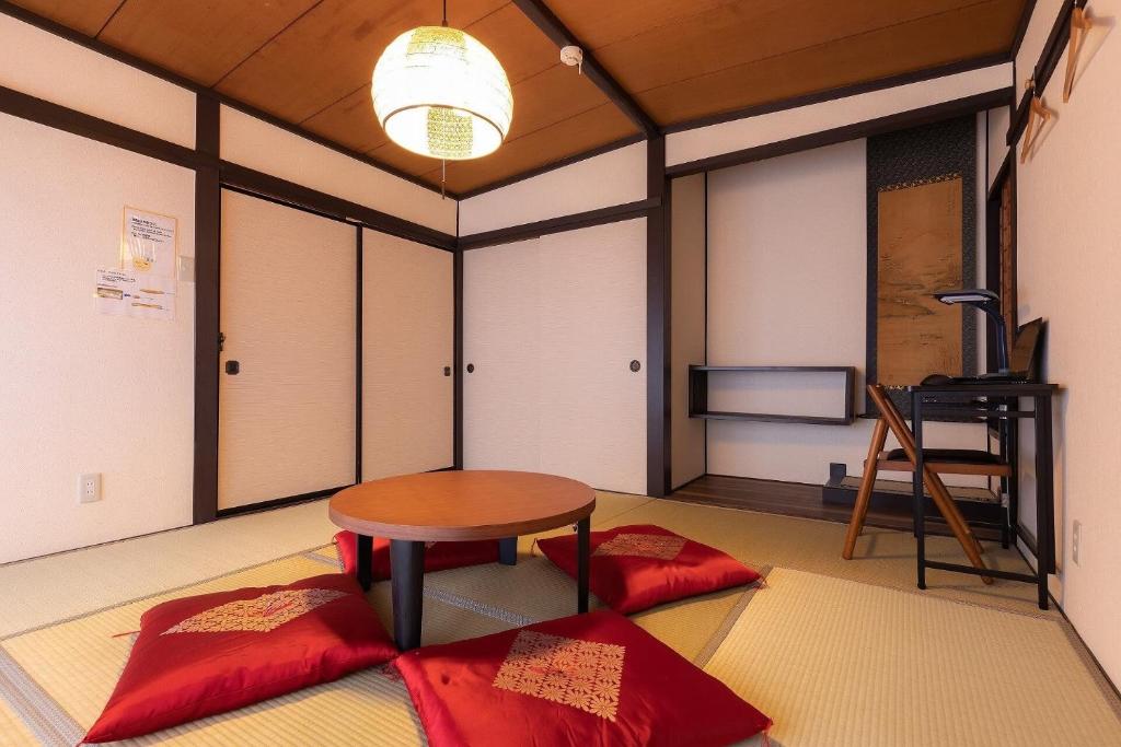 a room with a table and two red cushions at 松本はなれ in Matsumoto