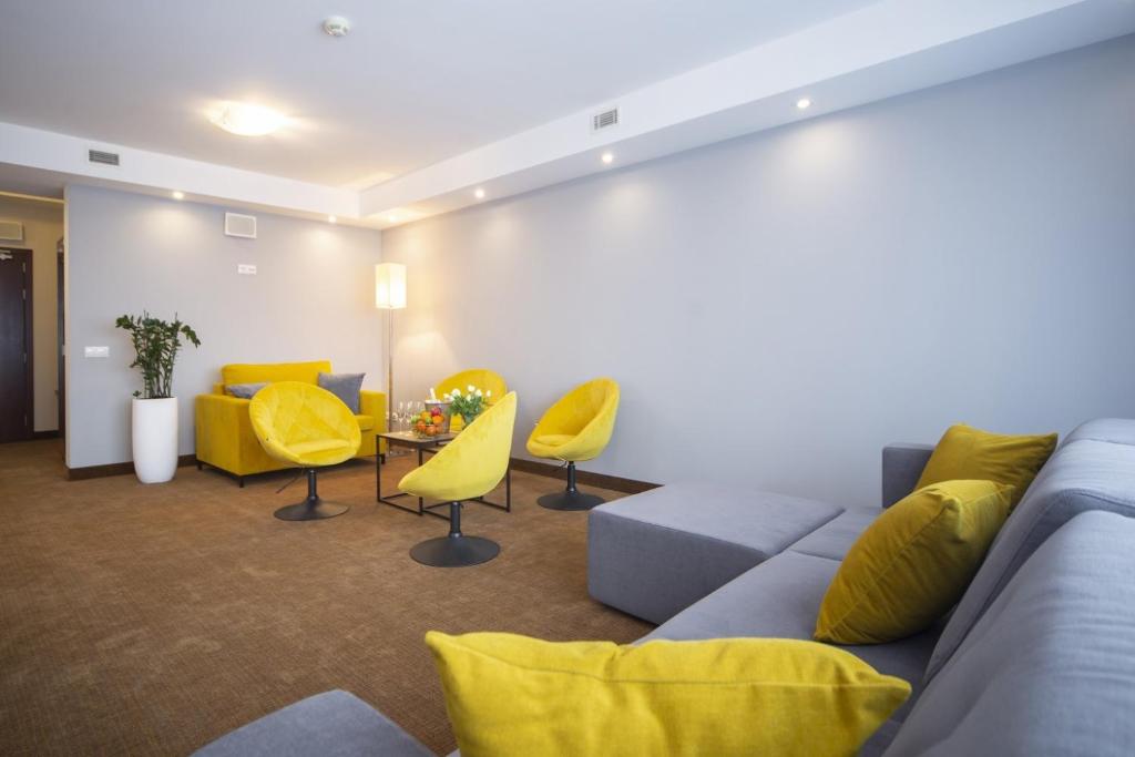 Spacious hotel lounge with yellow swivel chairs, grey sofa and coffee table, bright relaxed vibe