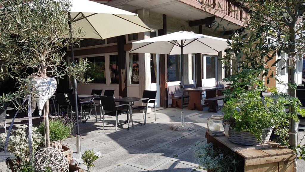 een patio met tafels, stoelen en parasols bij Hotel Sporting in Marbach