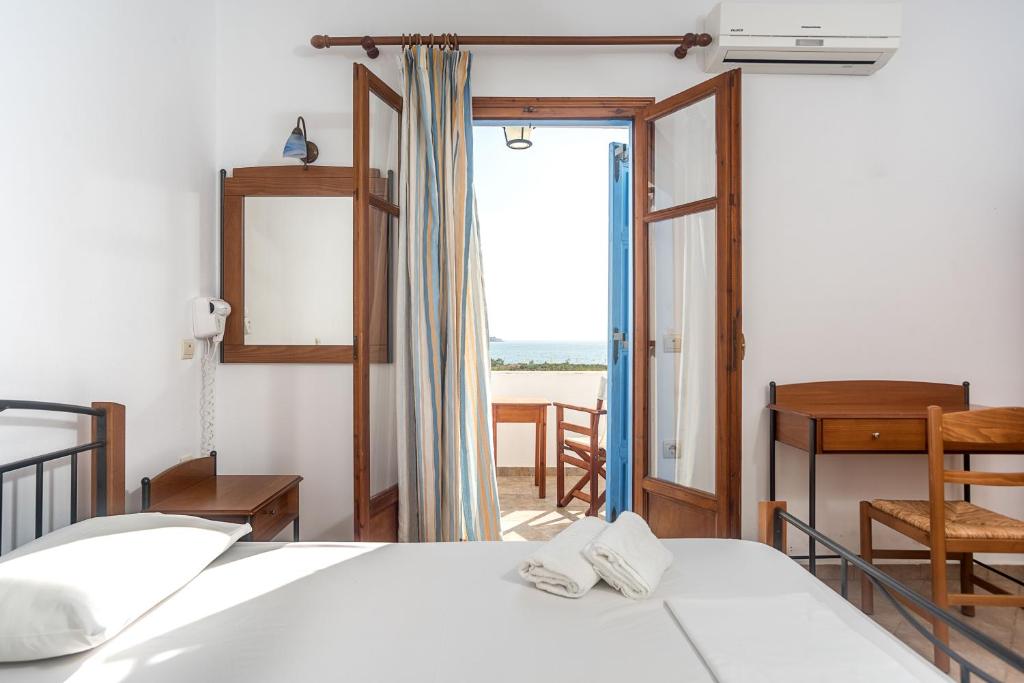 1 dormitorio con 1 cama y puerta a una ventana en Amodari studios on the beach en Plaka