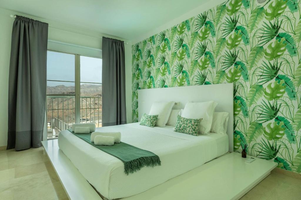 sypialnia z białym łóżkiem i dużym oknem w obiekcie Villa Happy Dreamer w mieście Puerto Rico de Gran Canaria