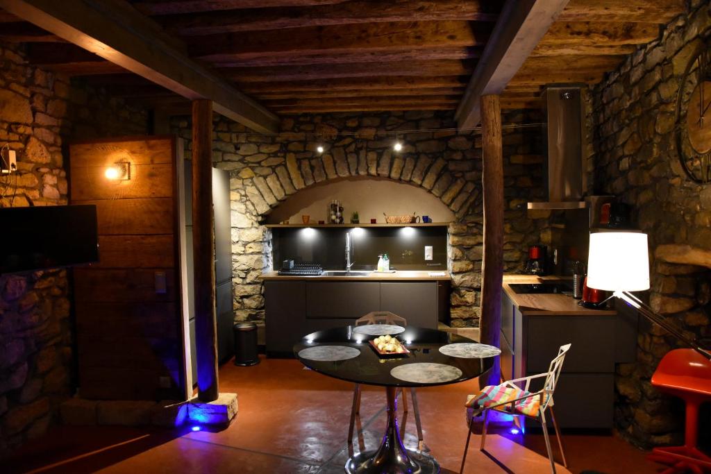 a kitchen with a table in a room with a stone wall at Caveau Contemporain KV'O37 in Arbois
