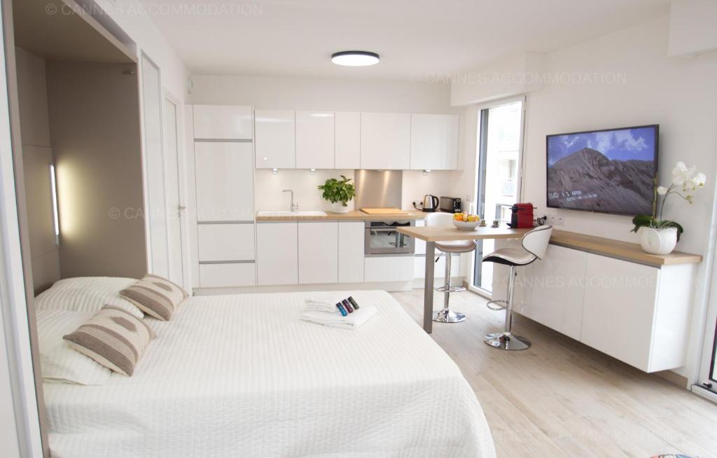 a white room with a bed and a desk in it at Brand new studio in the heart of Cannes in Cannes