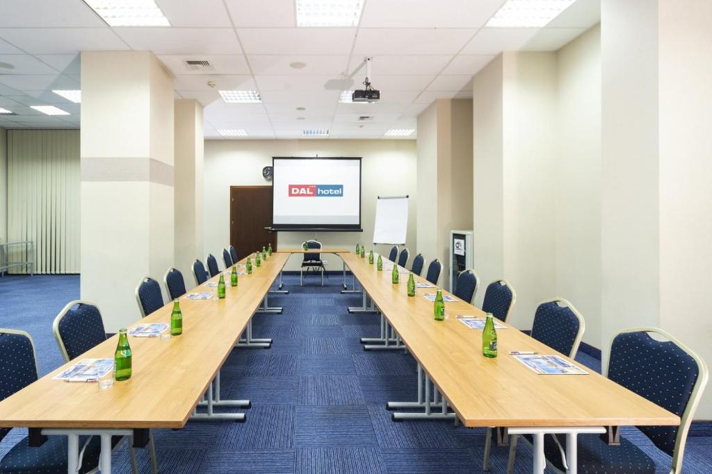 Conference room arranged U-shape with wooden tables, blue chairs and projected DAL hotel logo