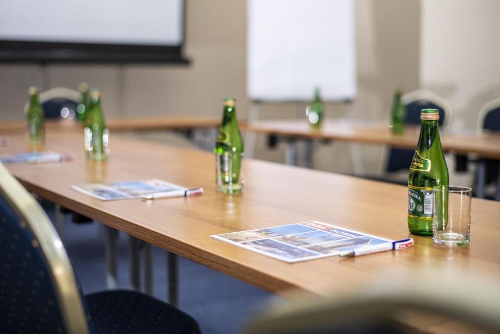 Close-up meeting table with brochure, pen, glass, and green mineral water bottle.