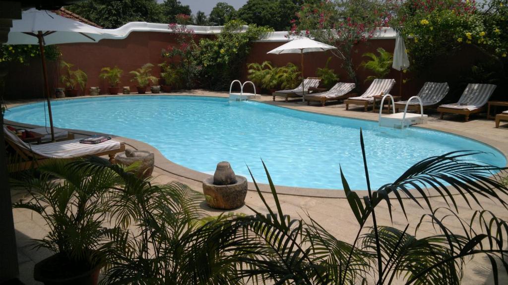 a large swimming pool with lounge chairs and an umbrella at Raheem Residency in Alleppey