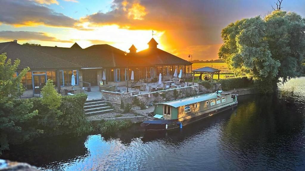 a boat parked in front of a house on a river at Dolphin Hotel Cambridge in St. Ives