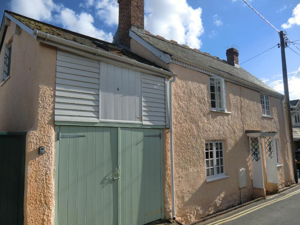 a building with a green garage door on a street at Heydons House - Lovely Seaside Cottage in Sidmouth