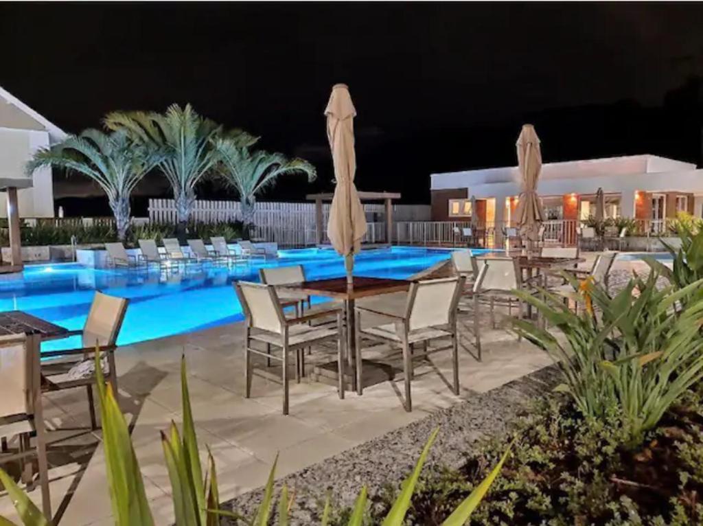 un patio con mesa y sillas junto a una piscina en Morro das Pedras, Santa Catarina, Brasil, en Florianópolis