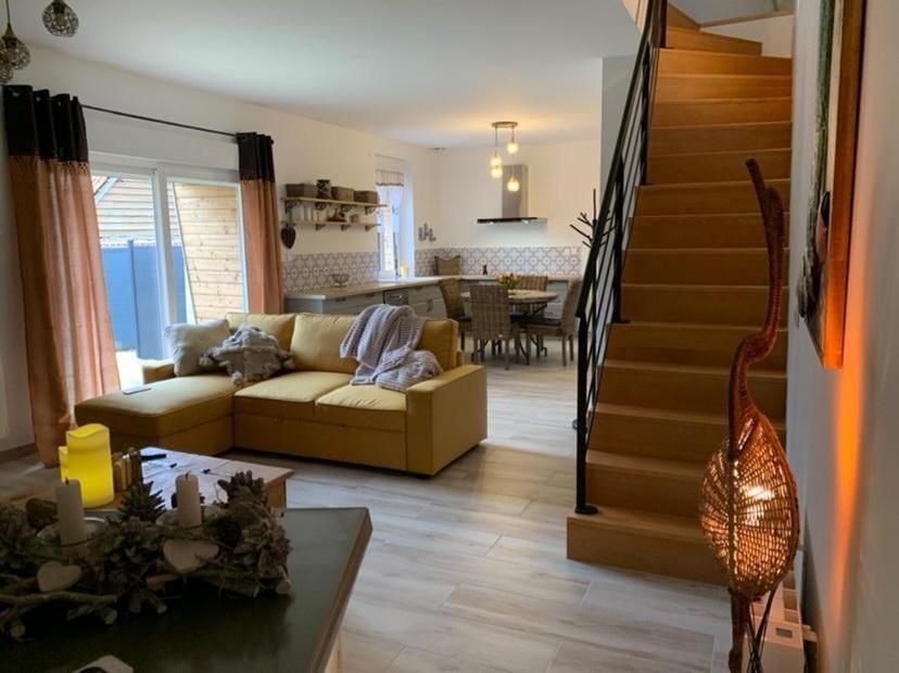 salon z kanapą i schodami w obiekcie La grange du bois w mieście Fresnicourt-le-Dolmen