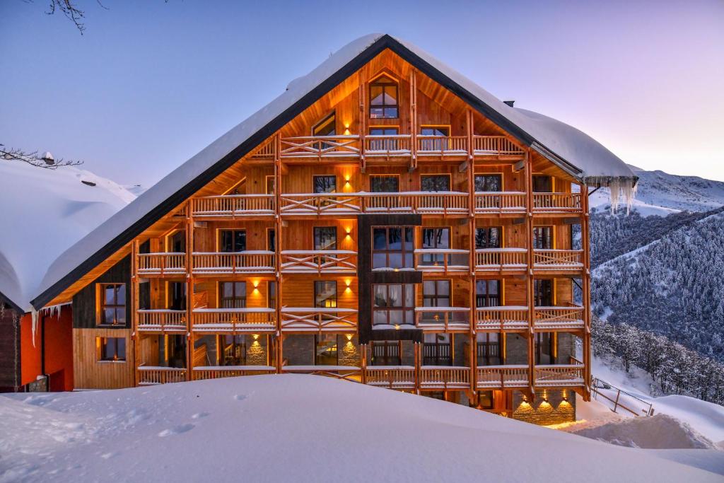 un grande edificio in legno con neve di fronte di Chalet Everest - Luxury Apartments a Prato Nevoso