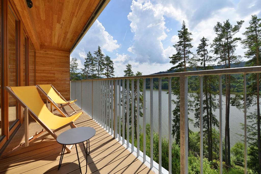 a wooden balcony with a chair and a table on it at Element Lakeside Apartments in Lipno nad Vltavou