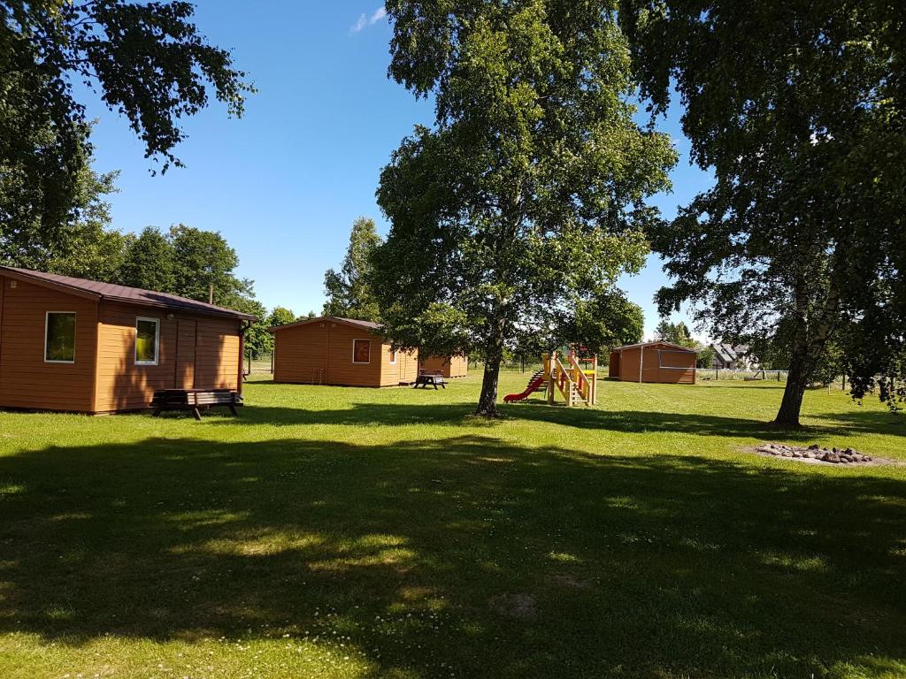 einen Hof mit einem Haus und einem Spielplatz in der Unterkunft Kempings Stieres un Mājas Virtuve in Upesgrīva